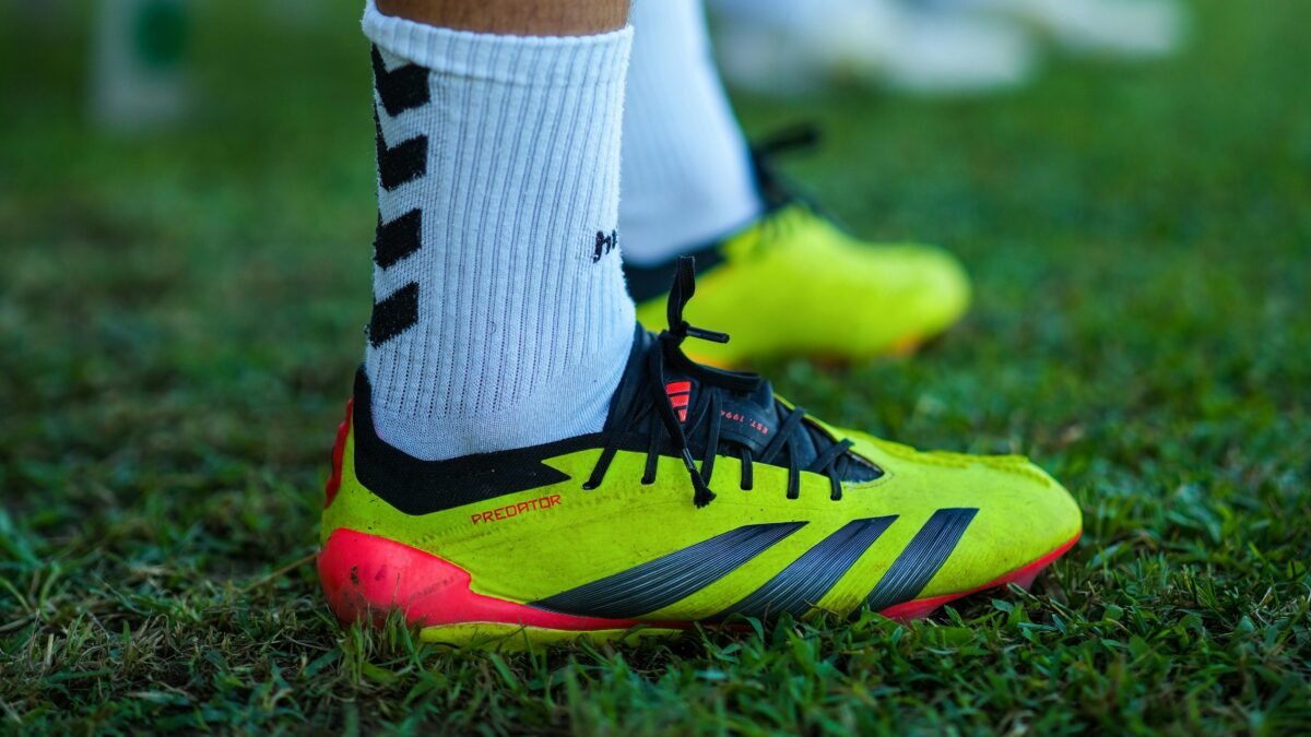 Bright football boots on green grass during a sunny day practice.