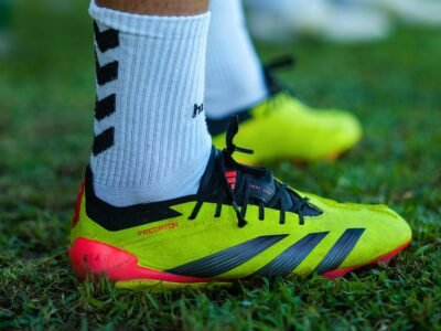 Bright football boots on green grass during a sunny day practice.